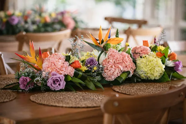 Centro de mesa alargado de claveles rosados, hortensias, rosas lilas y aves del paraíso