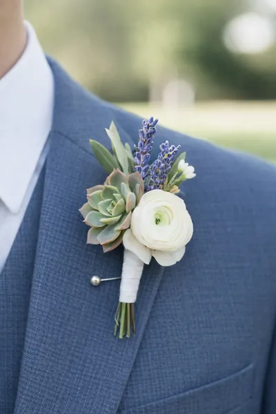 Boutonnière de suculenta, rosa blanca y lavanda en un traje azul
