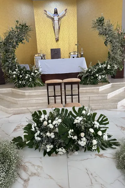Altar de iglesia con arcos de follaje y arreglos de flores blancas