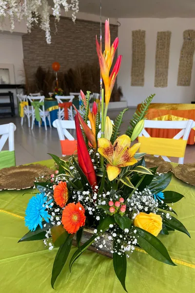 Arreglo de mesa con heliconias, lirios naranjas, rosas y gypsophila